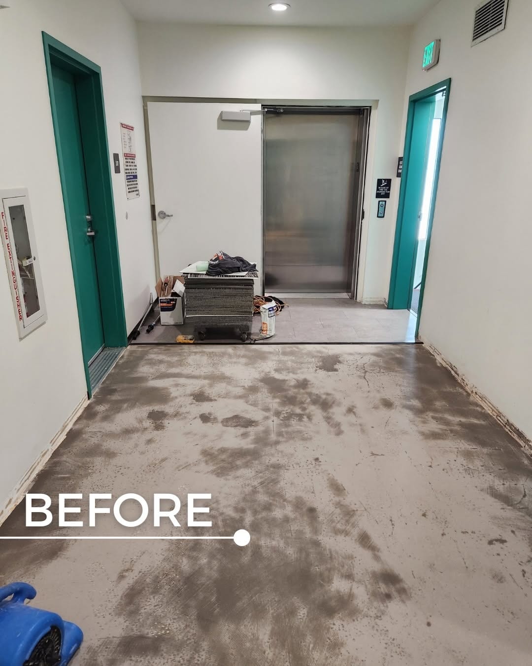 Elevator lobby with bare stained concrete floor before new flooring was installed