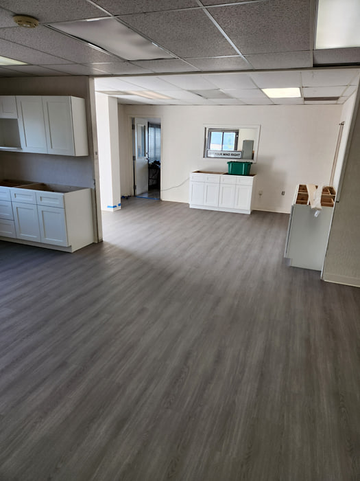 Open-plan commercial space finished in grey glue-down vinyl plank